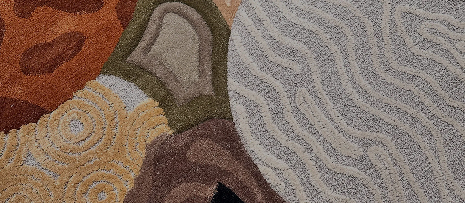 Close-up of textured multicolored carpet with abstract organic patterns in earth tones including beige, brown, green, and rust.