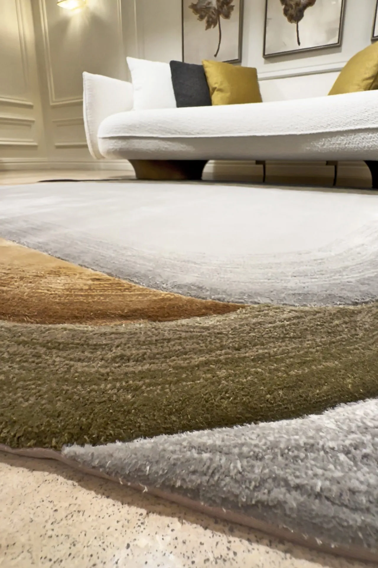 Close-up of a multi-colored textured area rug on a tiled floor with a white sofa and decorative pillows in the background.