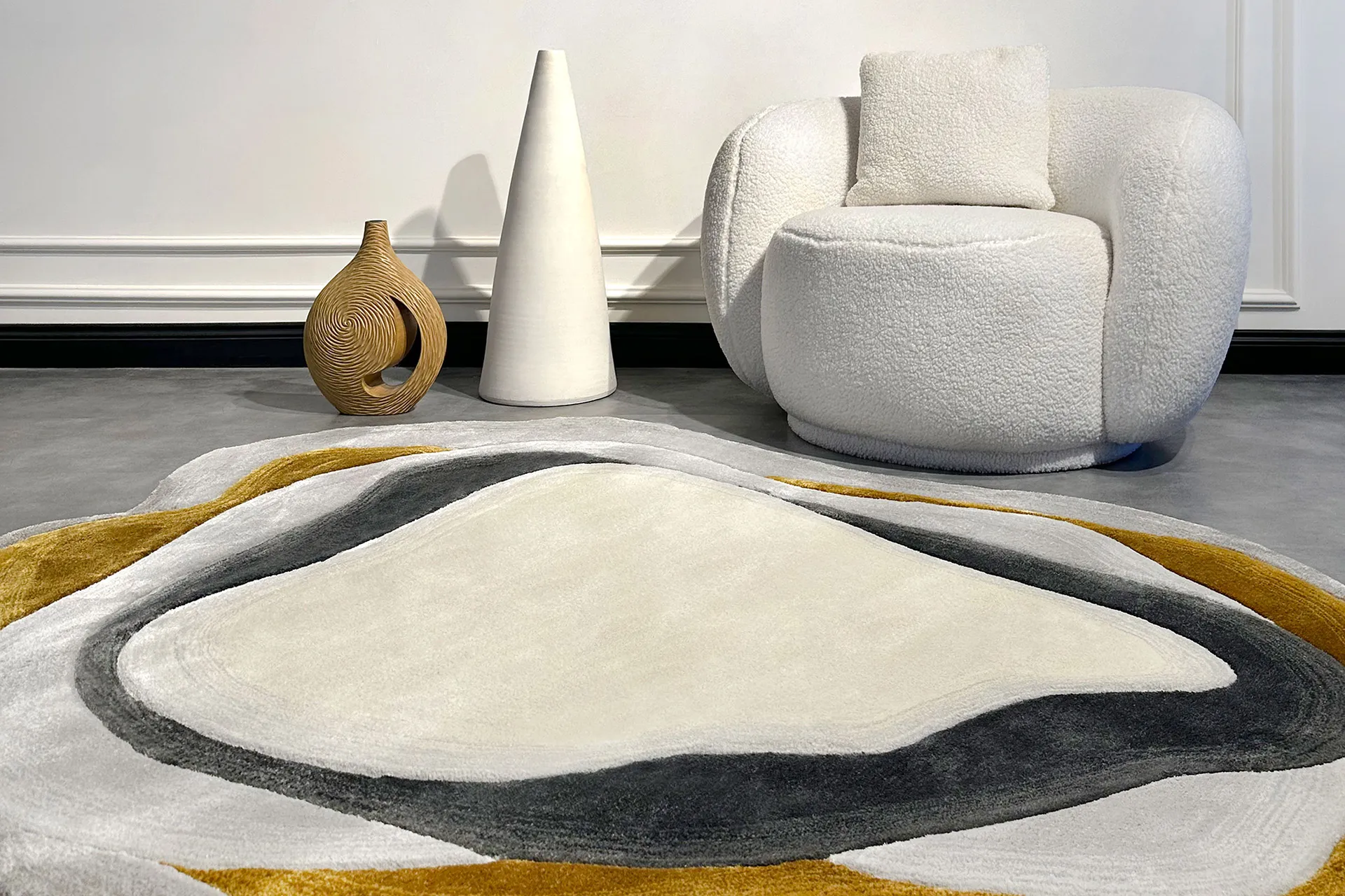 Modern interior with a plush white armchair, two decorative vases, and a multi-colored abstract rug in gray, white, and mustard tones.